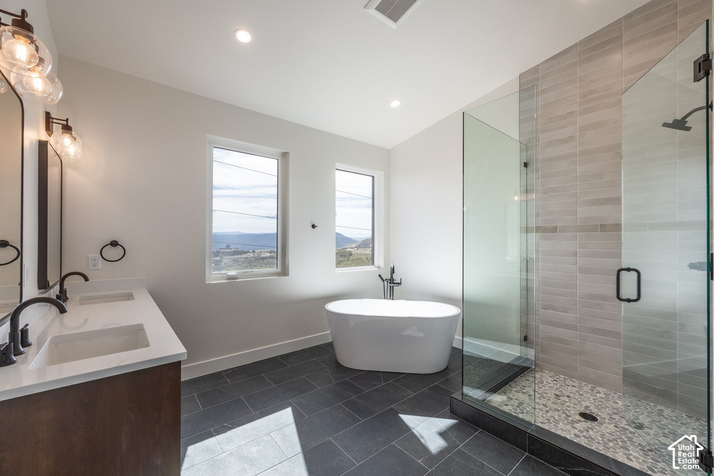 Dual vanity with quartz countertop, freestanding soaking tub, glass-enclosed shower with pebble floor, and matte black fixtures