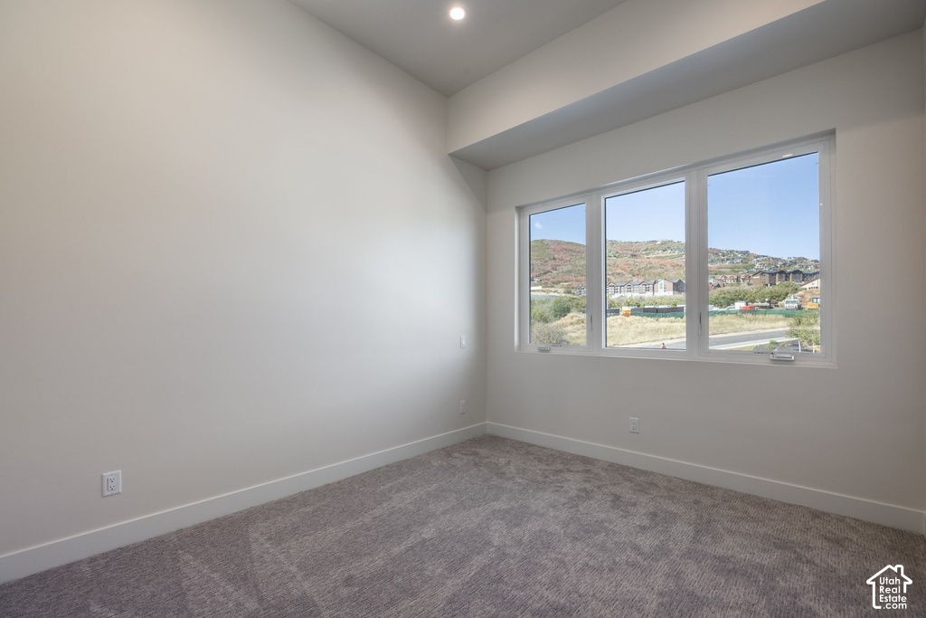Recessed ceiling lighting, a large triple-pane window, and textured gray carpet flooring