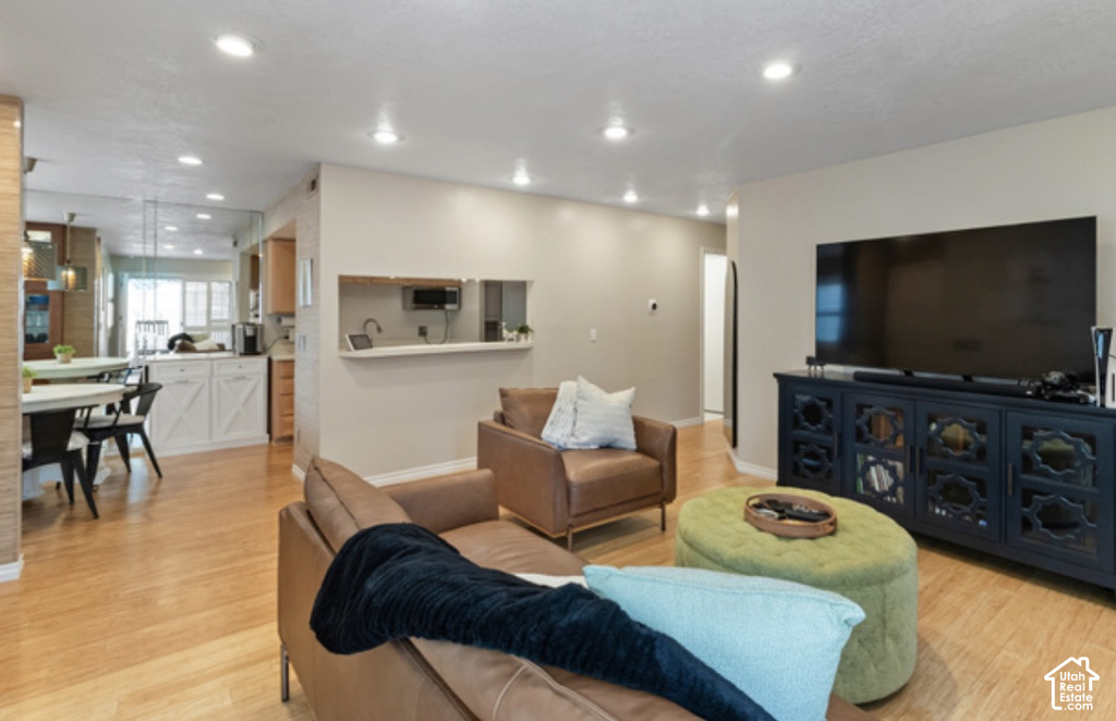 Open-concept living space featuring wood-finish flooring, recessed lighting, and a pass-through opening to the kitchen