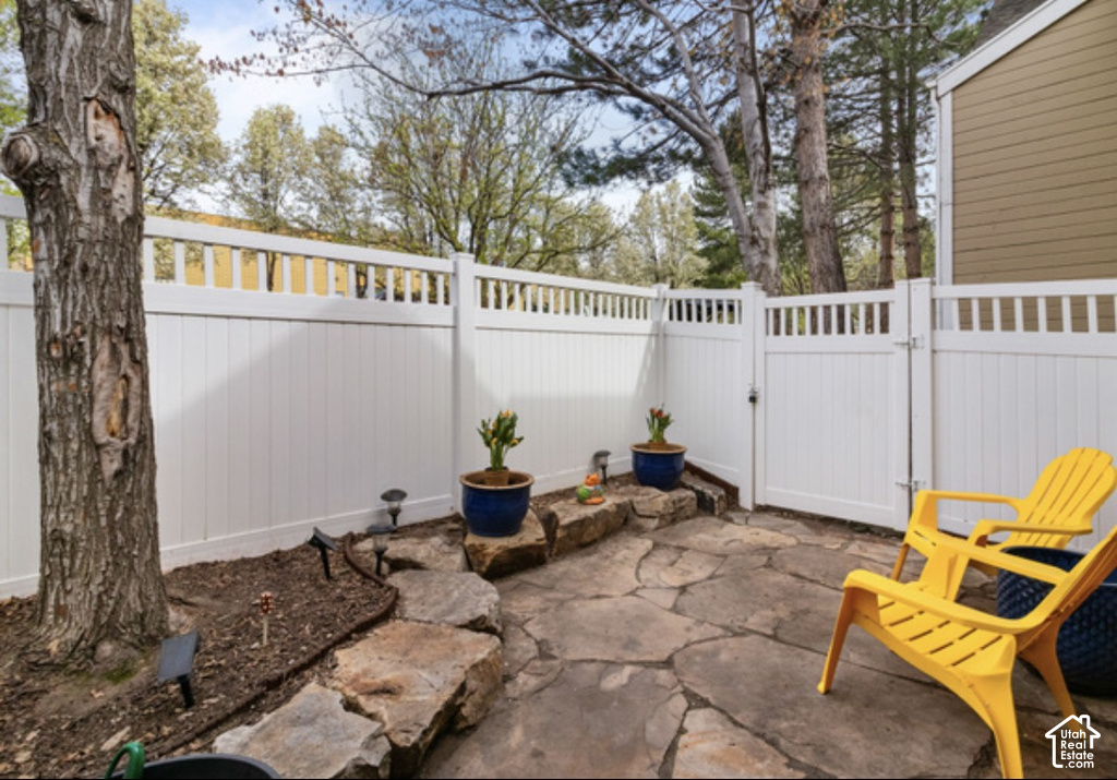 Private patio featuring flagstone paving, a white privacy fence, and mature trees