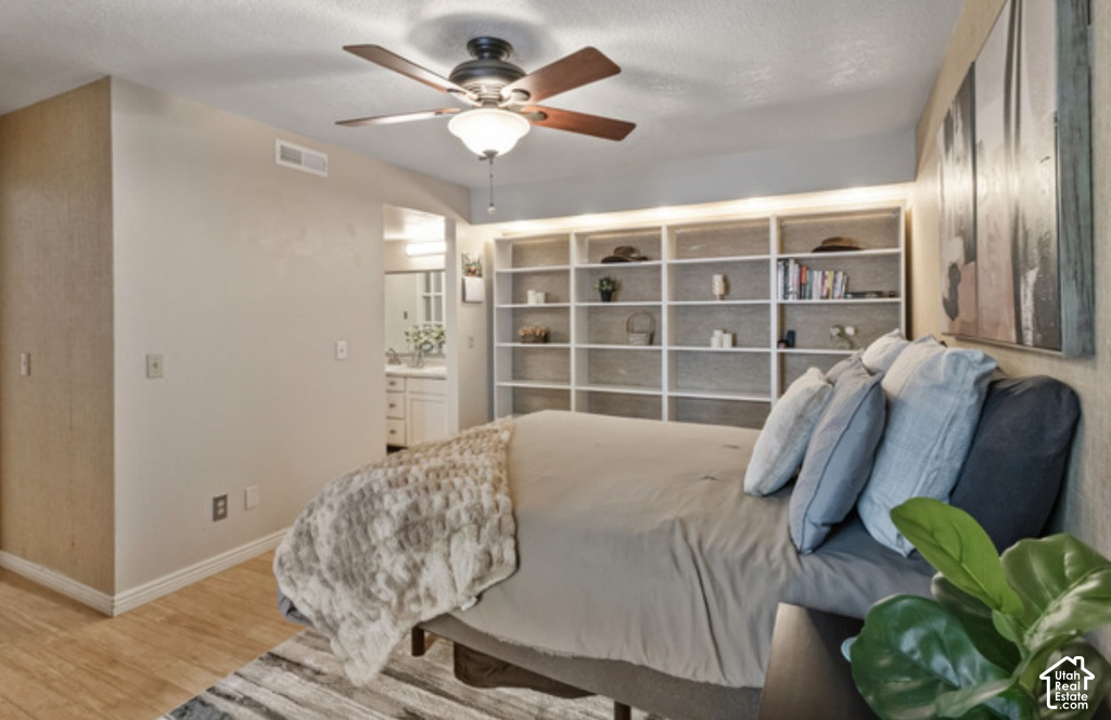 Built-in shelving with integrated lighting, wood-finish flooring, and a ceiling fan with light fixture