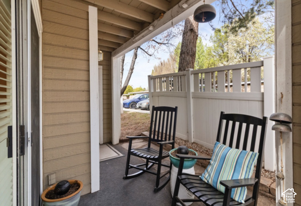 Covered patio with durable siding, white privacy fencing, and a concrete surface