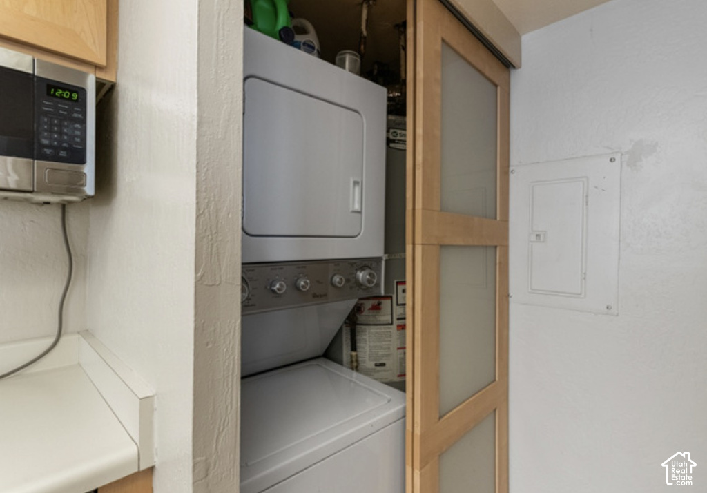Stackable washer and dryer, wood-finish sliding door with frosted glass panels, built-in microwave, and light-toned countertop