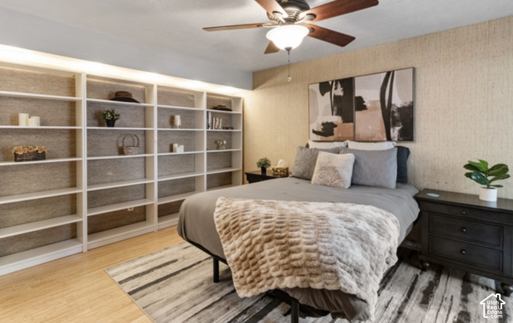 Built-in shelving with overhead lighting, wood-finish flooring, and a ceiling fan with integrated lighting