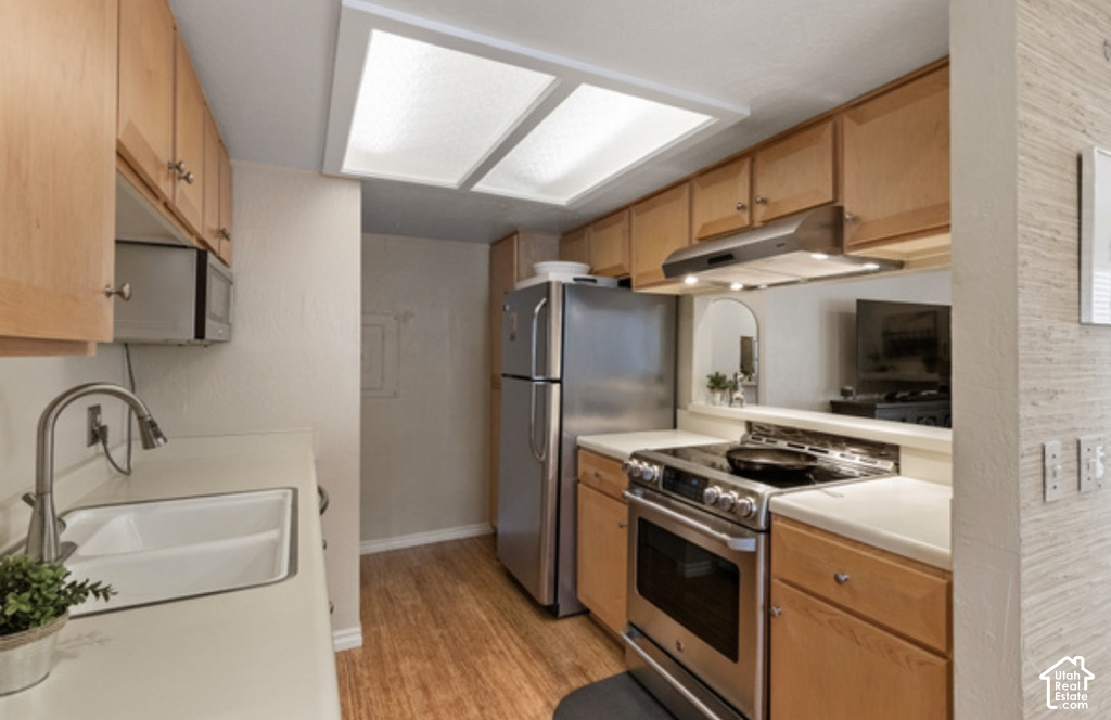 Kitchen featuring wood-finish cabinetry, stainless steel appliances, a double basin sink with a gooseneck faucet, and track lighting