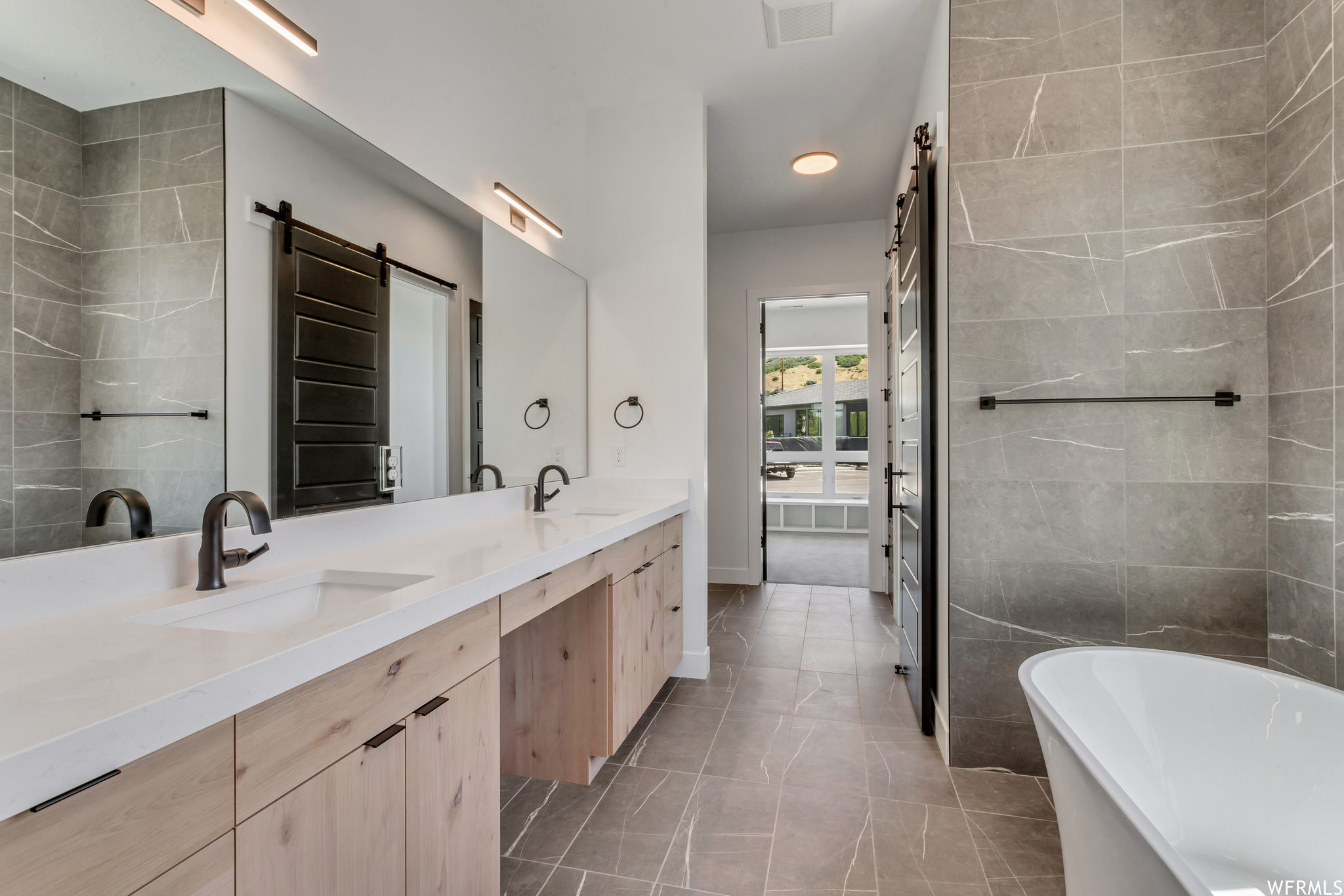 Dual sinks, soaking tub and floor to ceiling tile elevate this bath to luxury level
