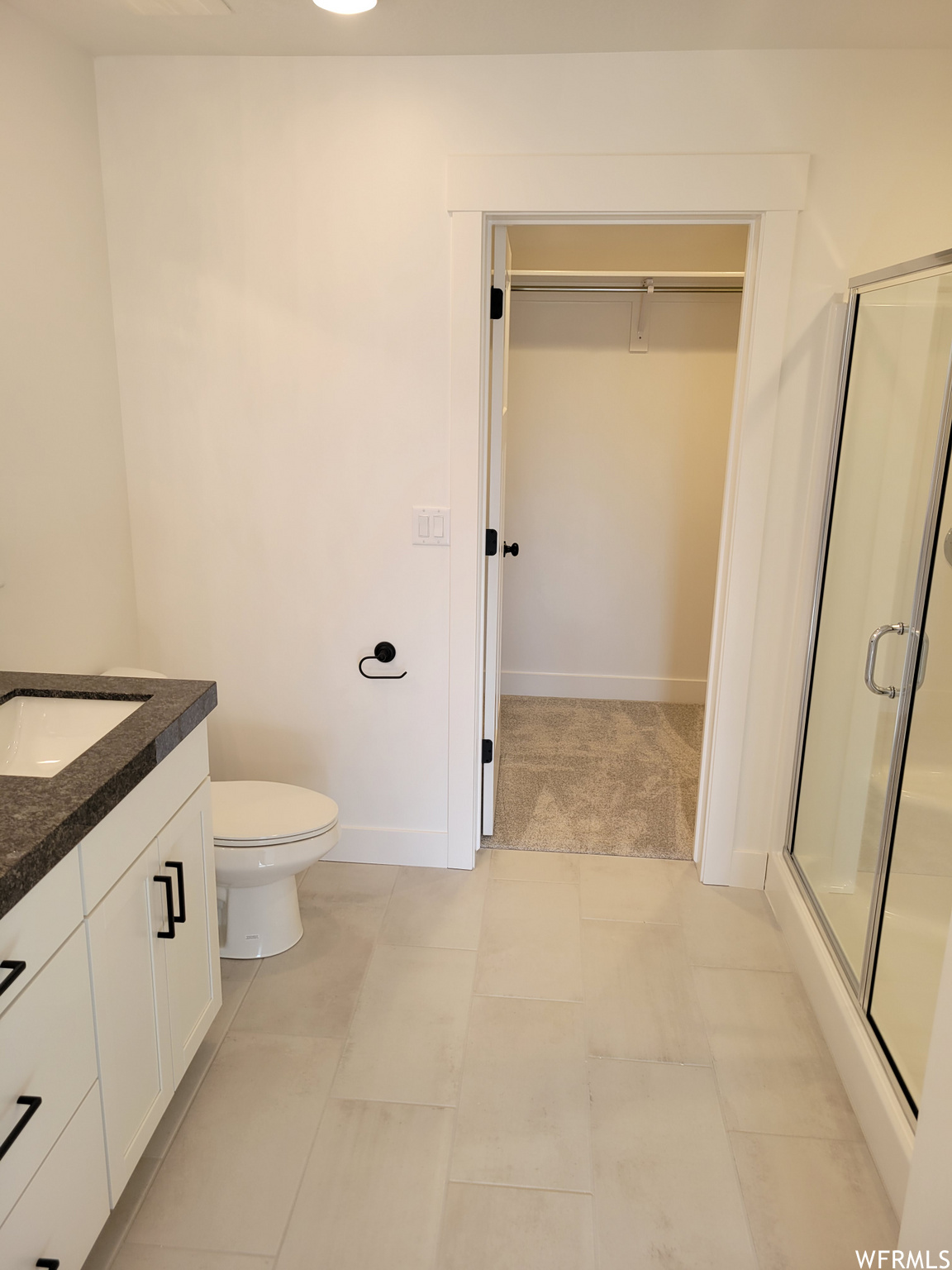 Full bathroom with tile flooring, toilet, shower cabin, and vanity