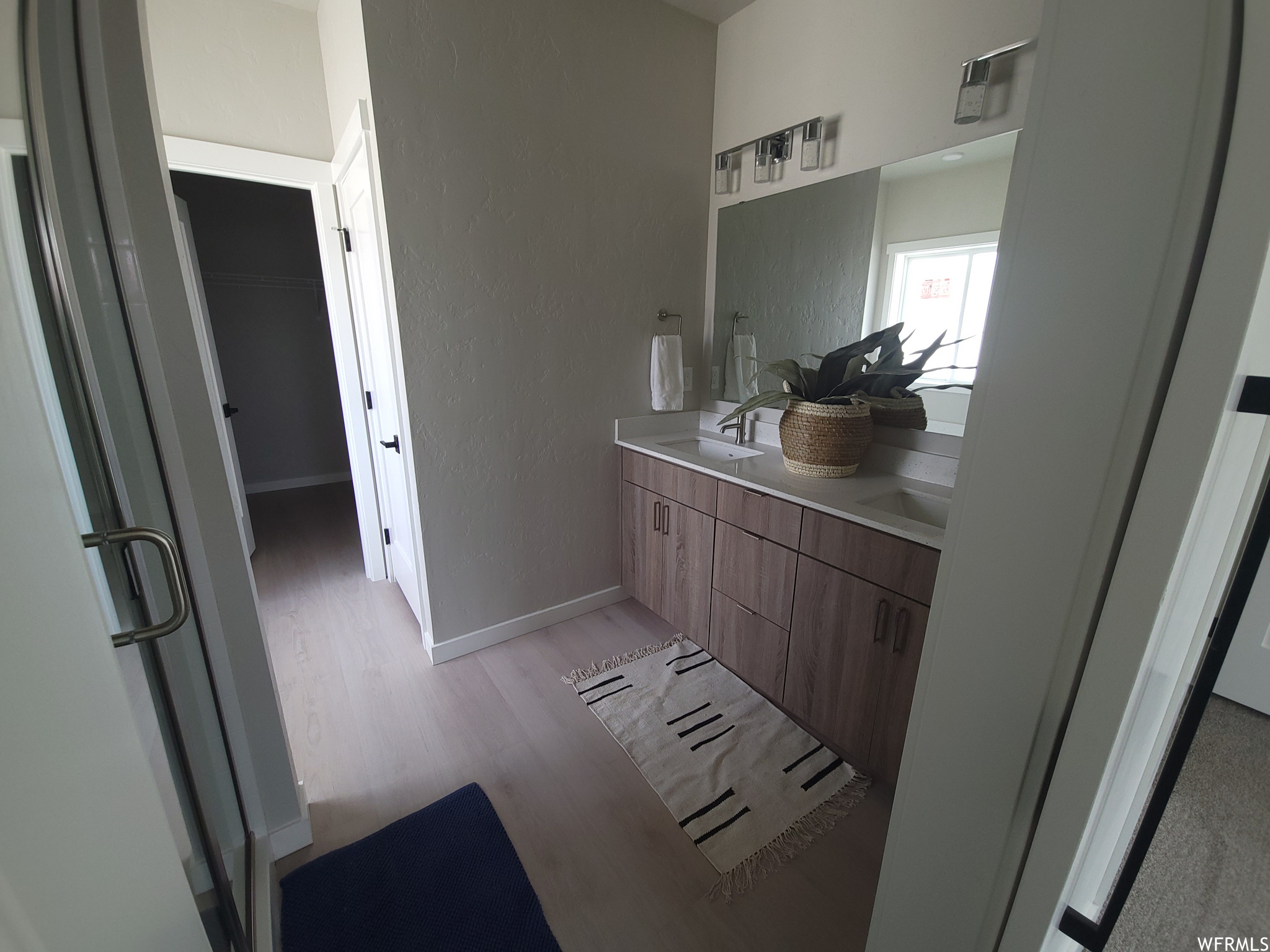 Bathroom featuring hardwood flooring, natural light, mirror, and his and hers large vanity