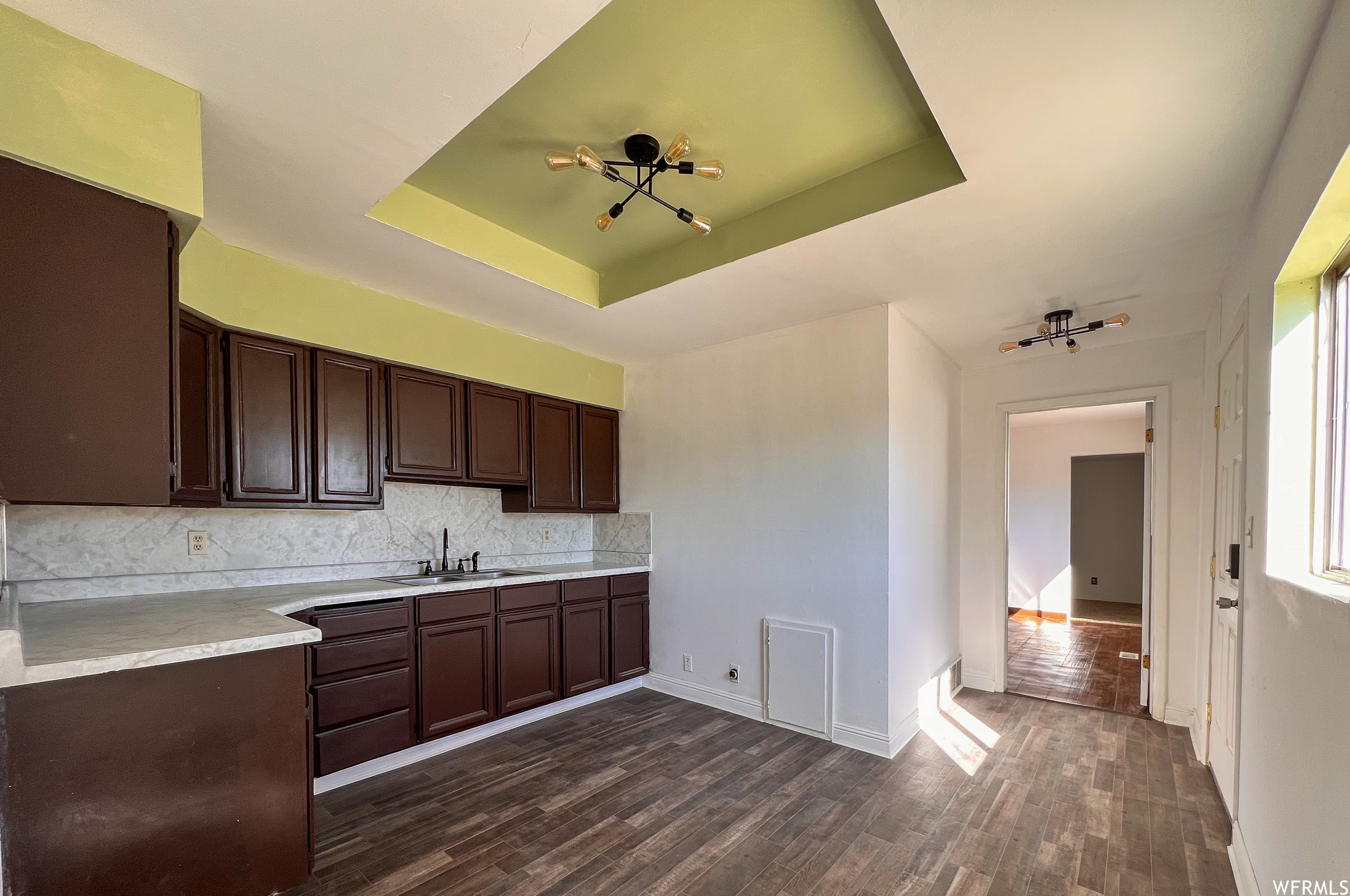 Kitchen with dark flooring, dark brown cabinets, and light countertops