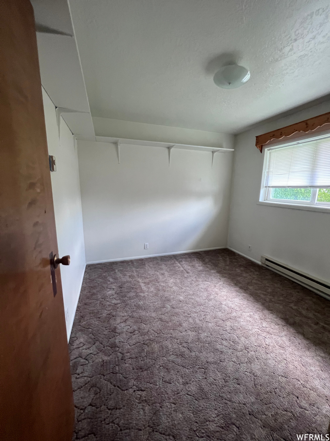 Spare room with a baseboard radiator, a textured ceiling, and carpet flooring