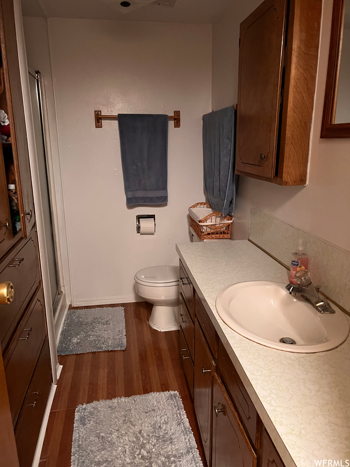 Half bathroom featuring wood-type flooring, toilet, and vanity