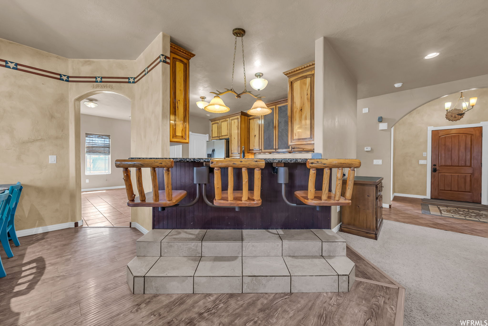 Kitchen featuring a breakfast bar area, refrigerator, light hardwood flooring, and brown cabinets