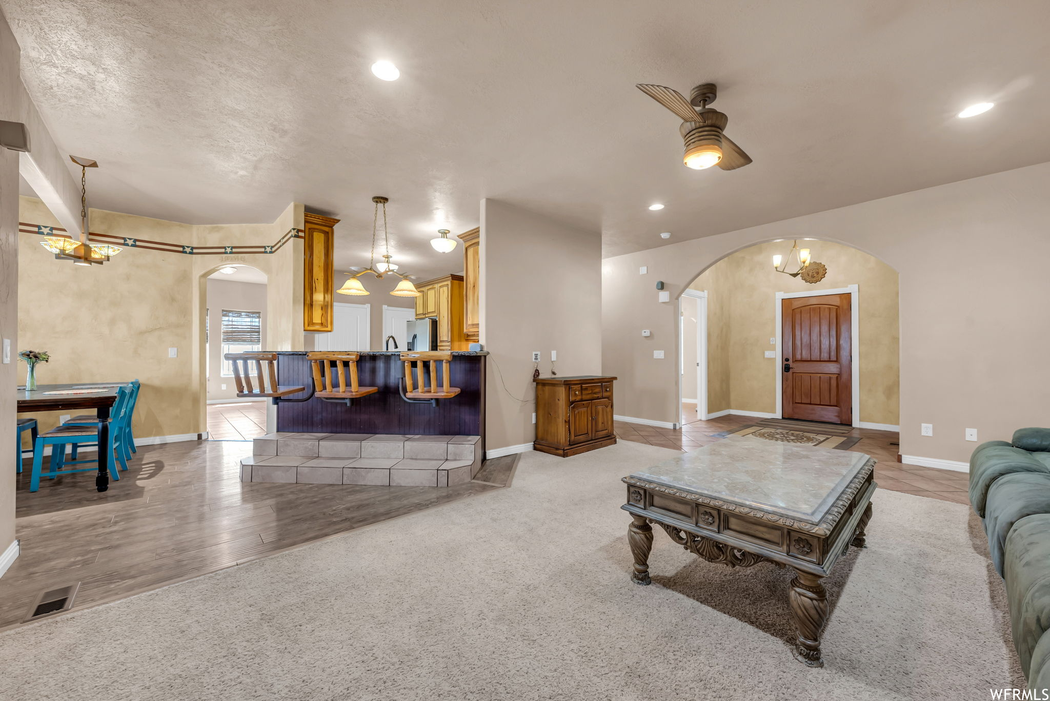 Hardwood floored living room with a breakfast bar area and natural light