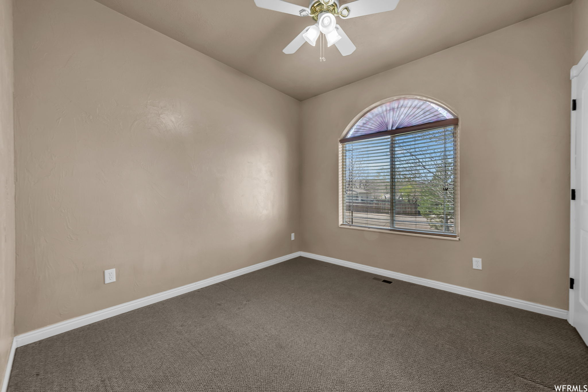 Carpeted empty room with a ceiling fan and natural light