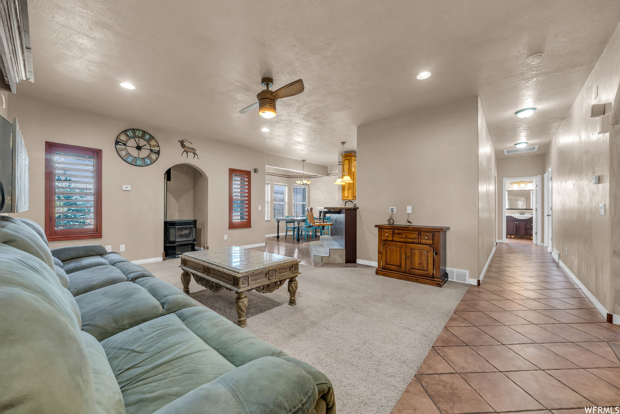 Carpeted living room featuring a ceiling fan and natural light