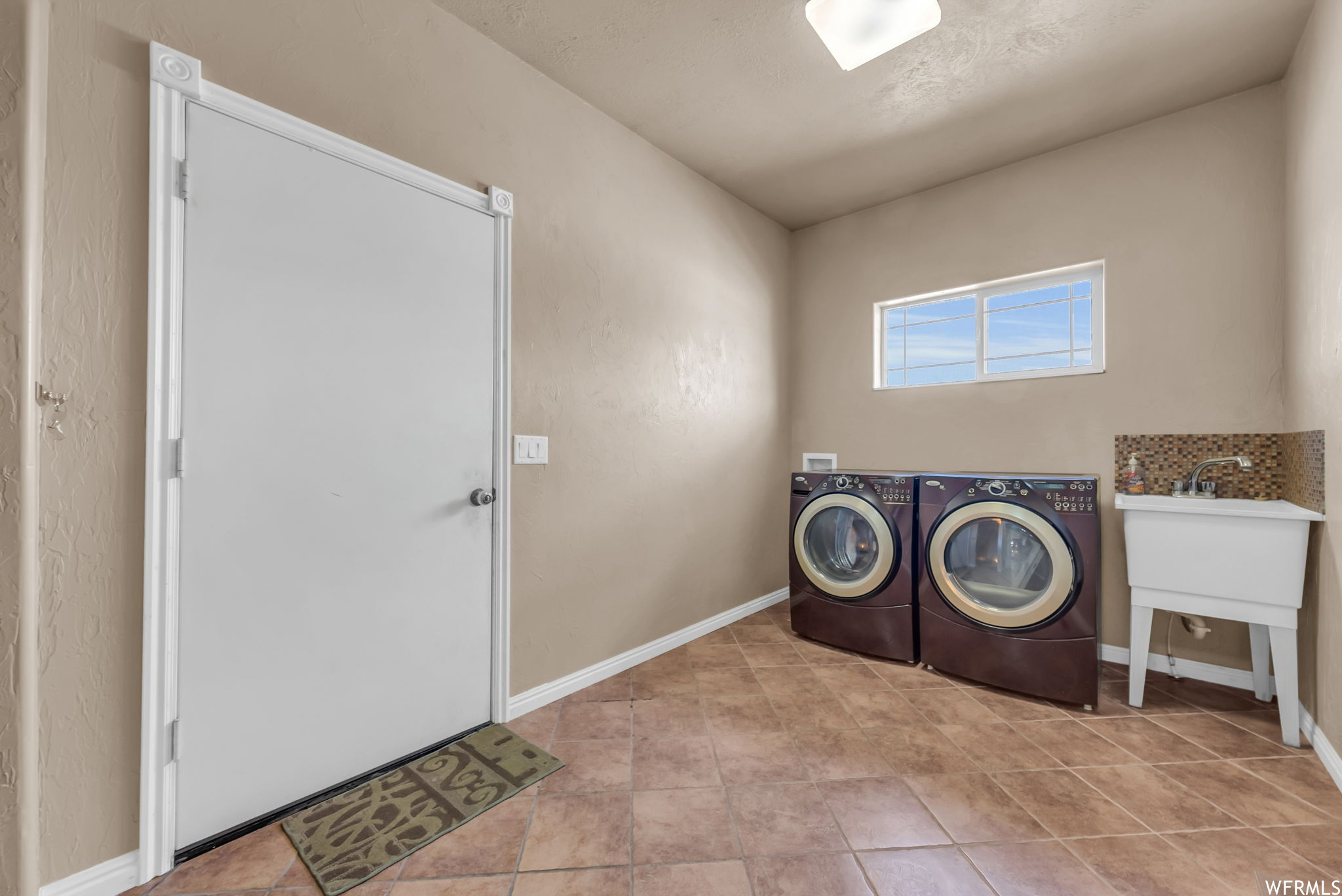 Laundry area featuring tile flooring, natural light, and separate washer and dryer