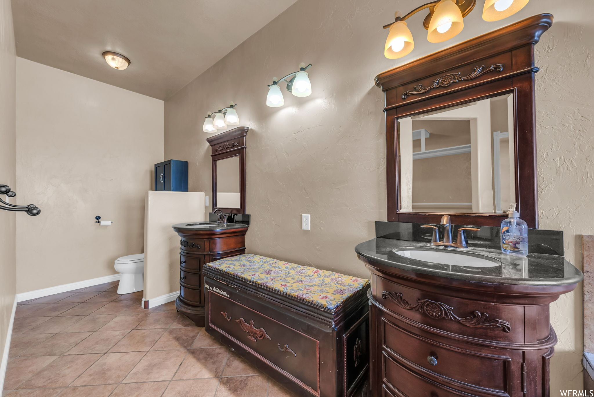 Half bathroom with tile floors, double sink vanity, mirror, and toilet