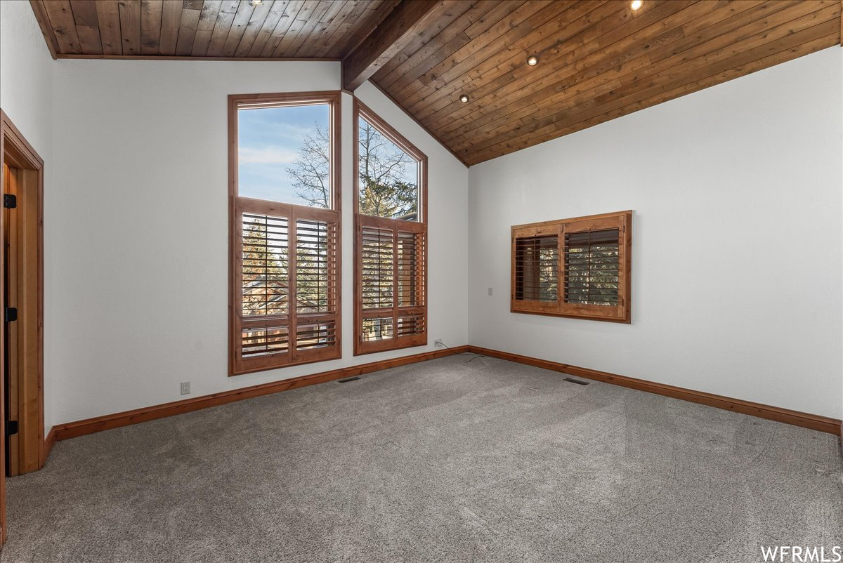 Unfurnished room featuring wood ceiling, beamed ceiling, carpet, and high vaulted ceiling