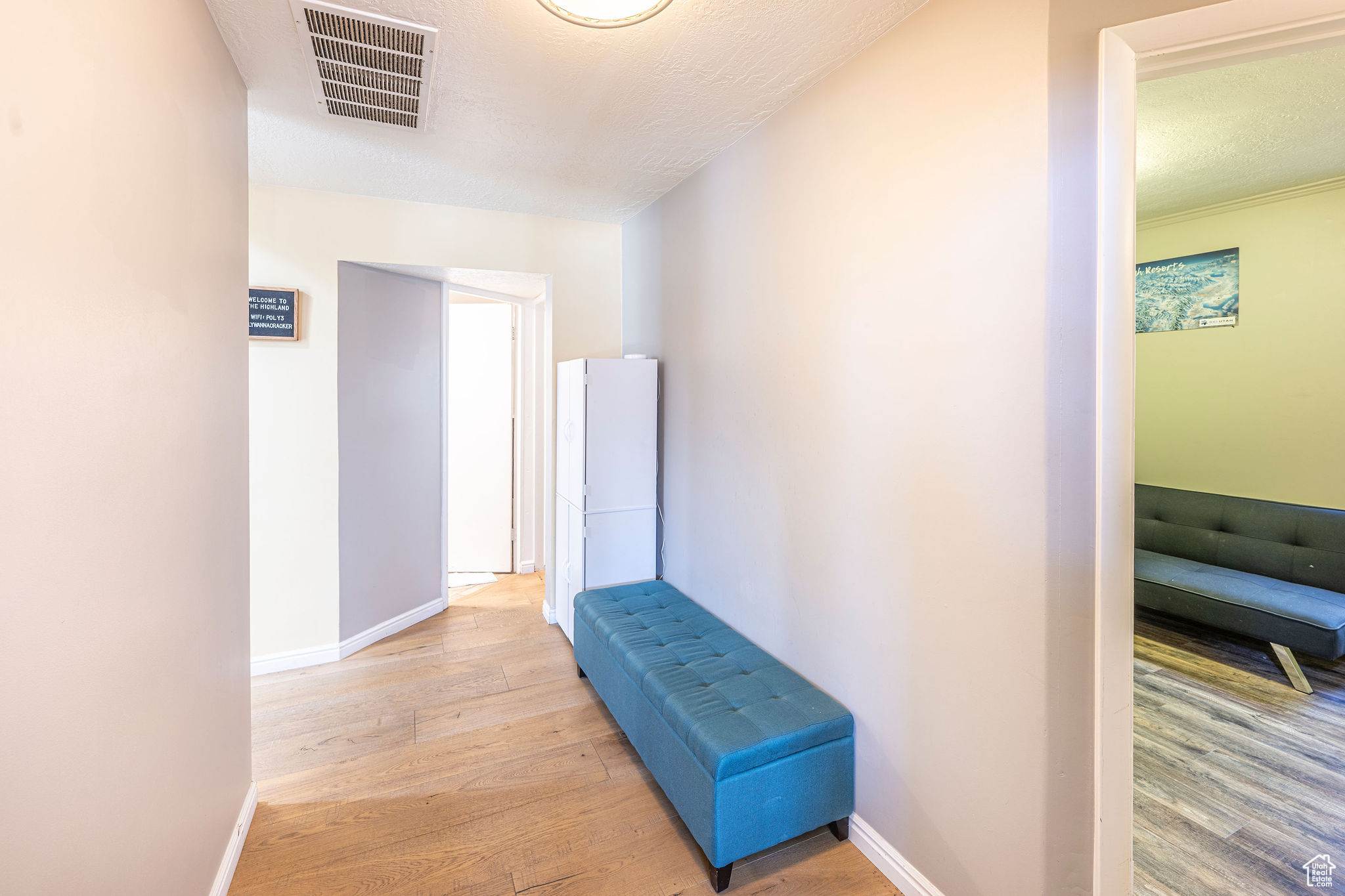 Hallway featuring a textured ceiling and light hardwood / wood-style floors