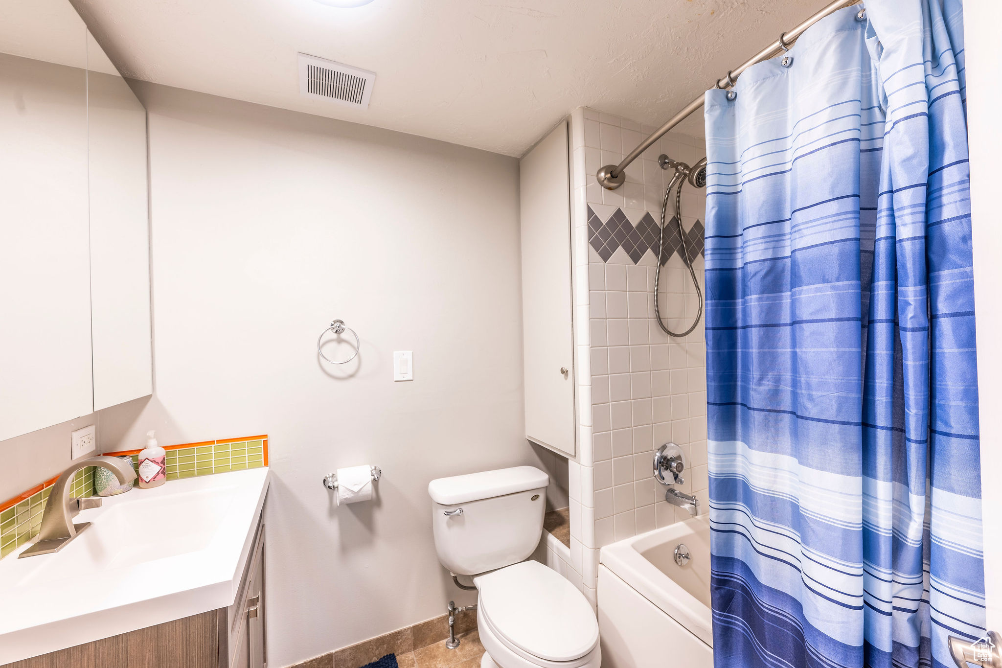 Full bathroom with toilet, vanity, and shower / bathtub combination with curtain