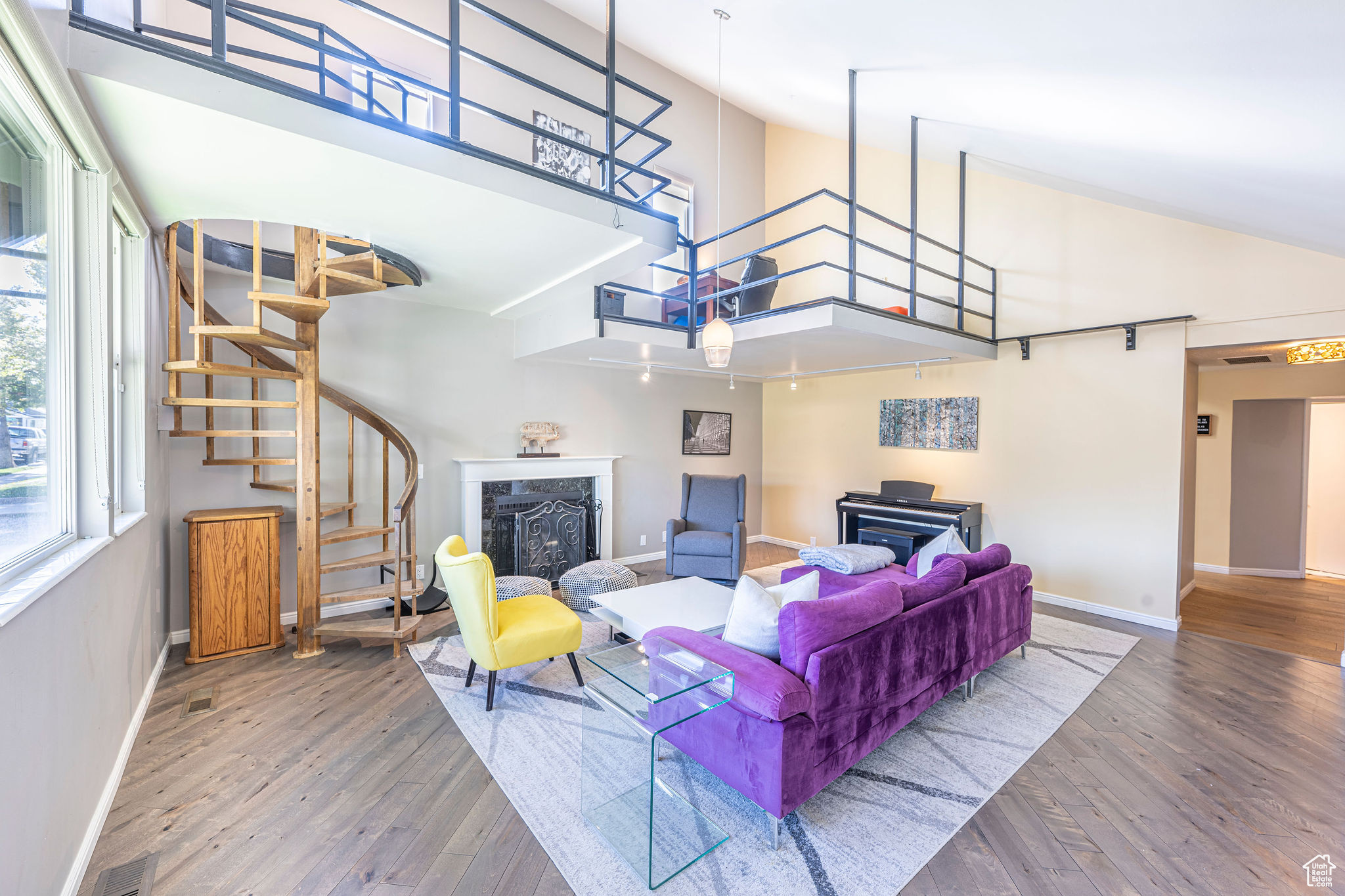 Living room featuring high vaulted ceiling, wood-type flooring, and a premium fireplace