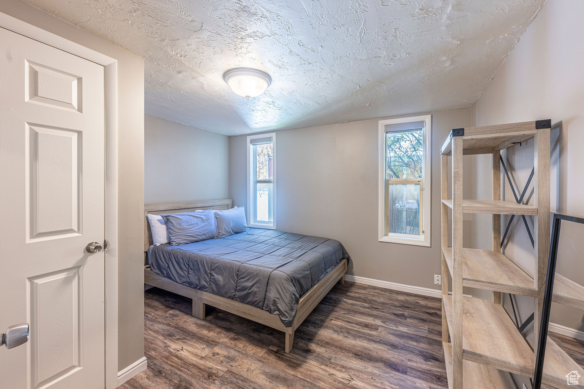 Bedroom with dark hardwood / wood-style flooring and a textured ceiling