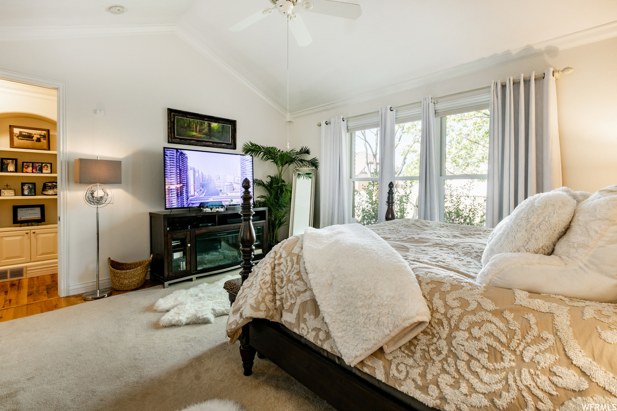 Hardwood flooring, crown molding, ceiling fan and a wall of windows complete the bedroom.