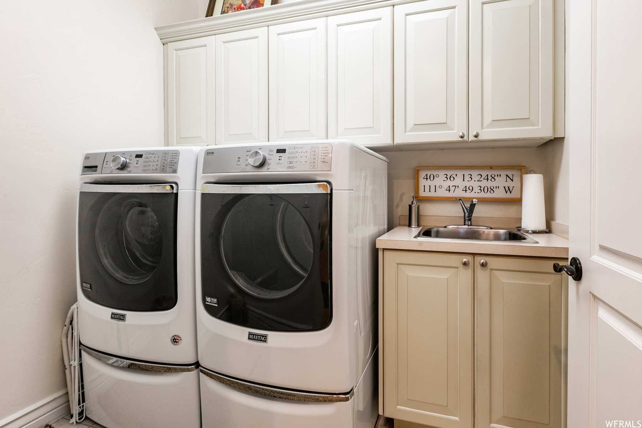 The laundry includes a sink, lots of storage and tile flooring.
