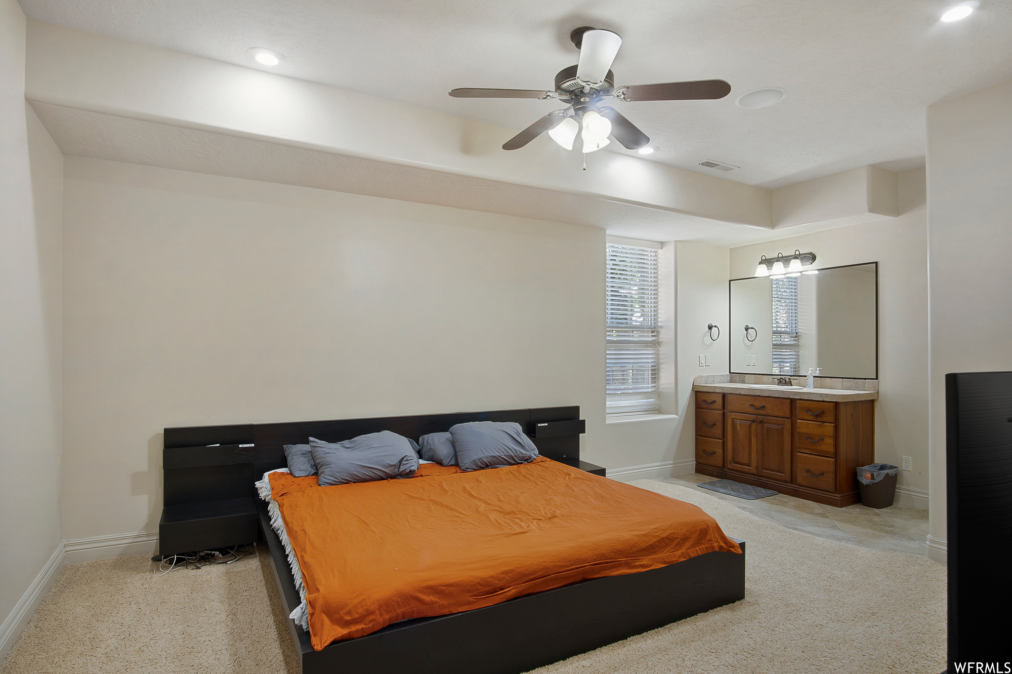 Carpeted bedroom with a ceiling fan and natural light, full bath