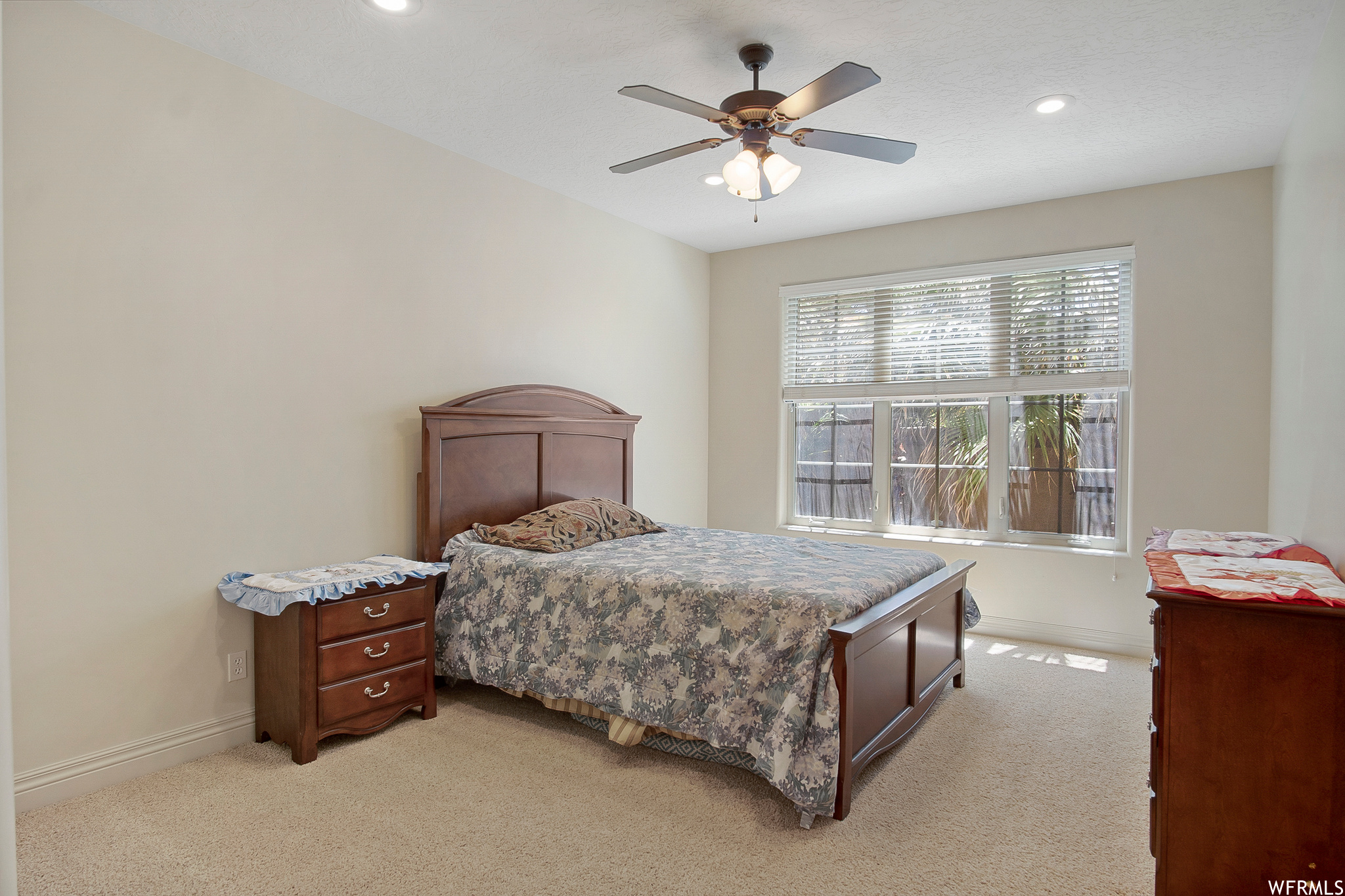 Carpeted bedroom with natural light and a ceiling fan