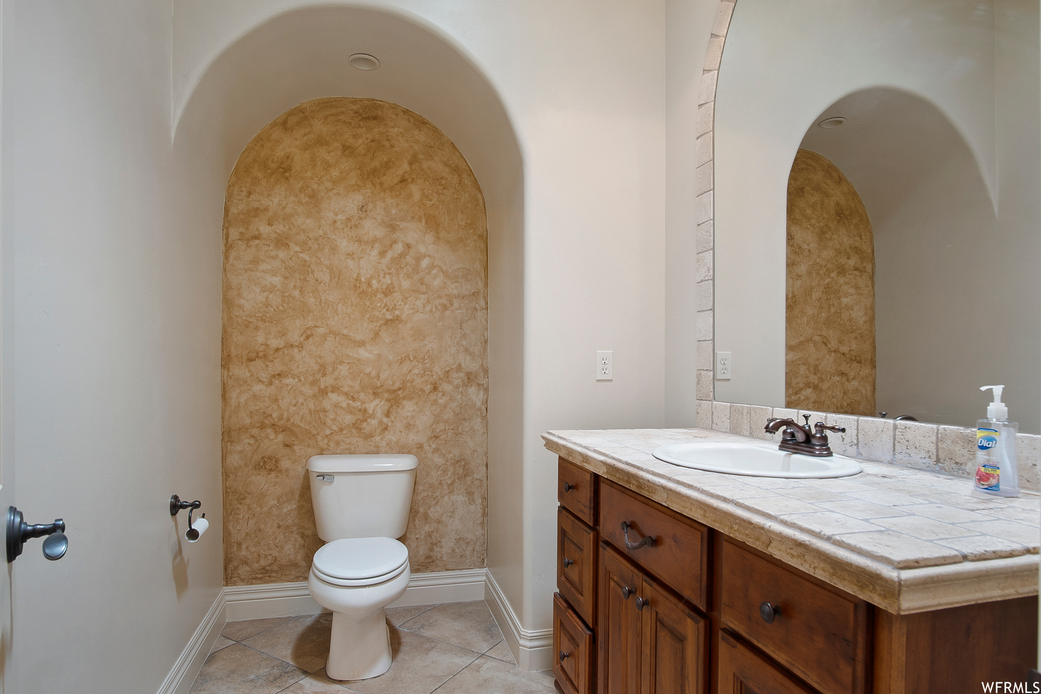 Half bathroom featuring tile flooring, toilet, mirror, and vanity