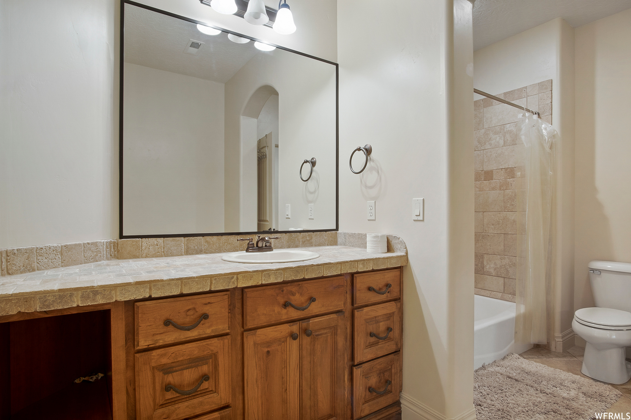 Full bathroom with mirror, toilet, shower / washtub combination, shower curtain, and vanity