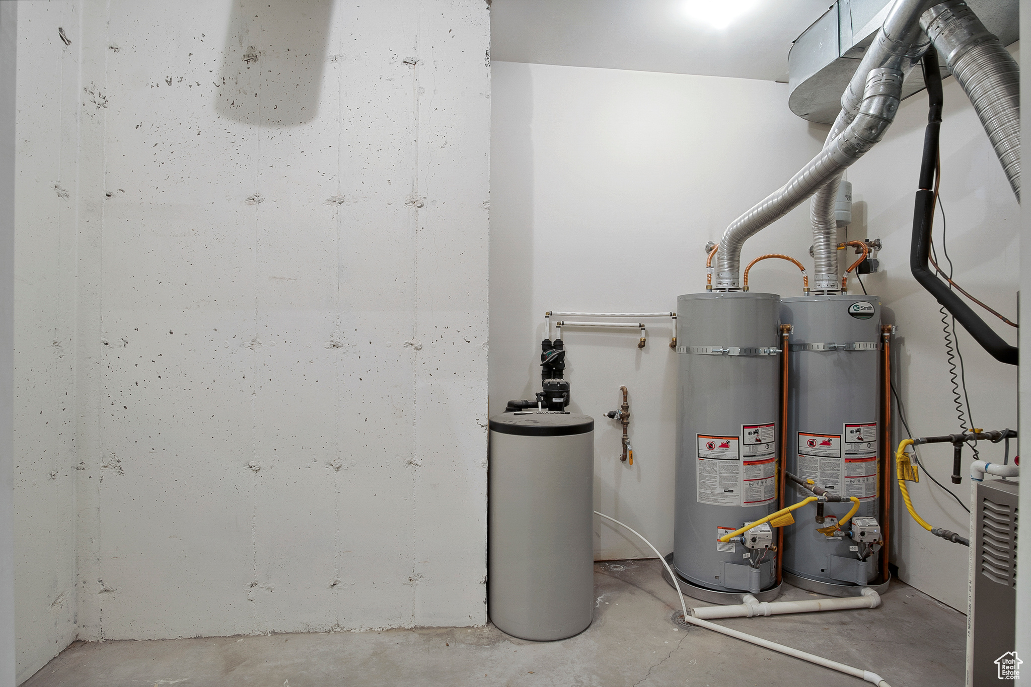 Utility room featuring strapped water heater