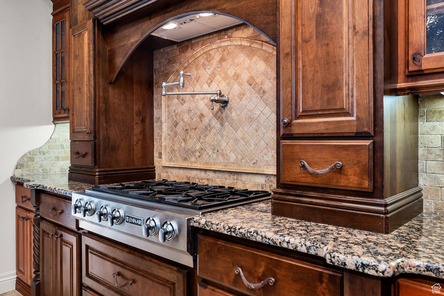 Kitchen featuring light stone countertops, tasteful backsplash, and stainless steel gas stovetop