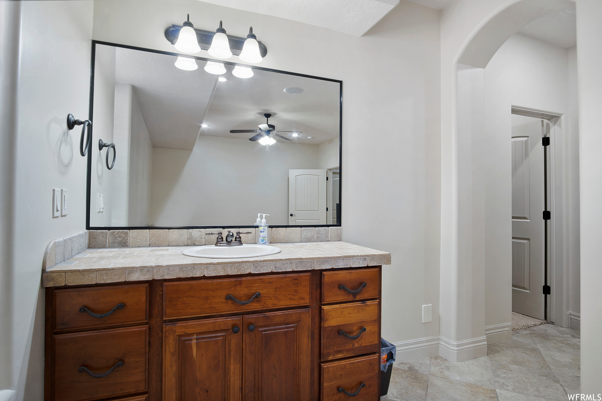 Bathroom with tile flooring, a ceiling fan, vanity with extensive cabinet space, and mirror