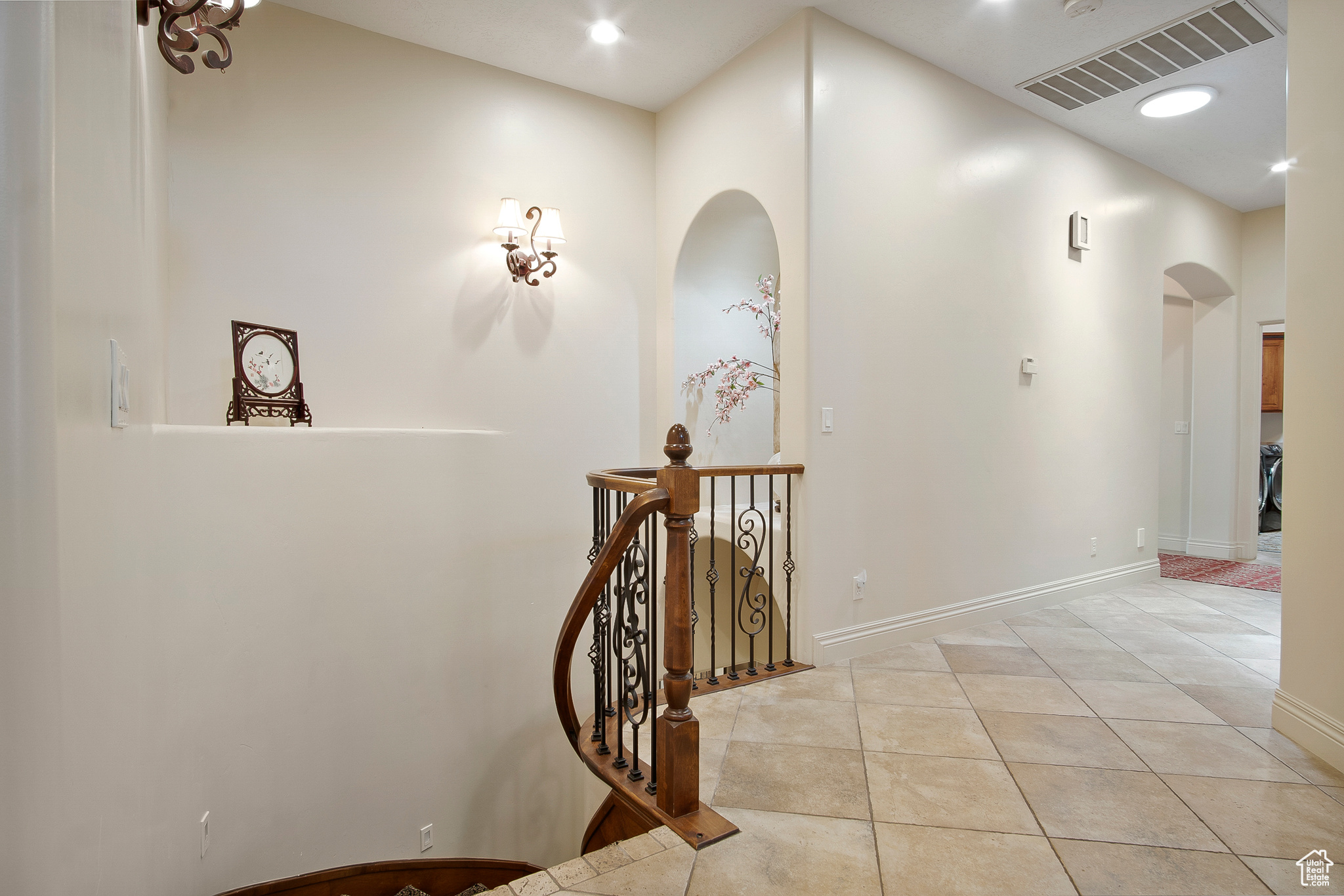 Corridor featuring a towering ceiling and light tile floors