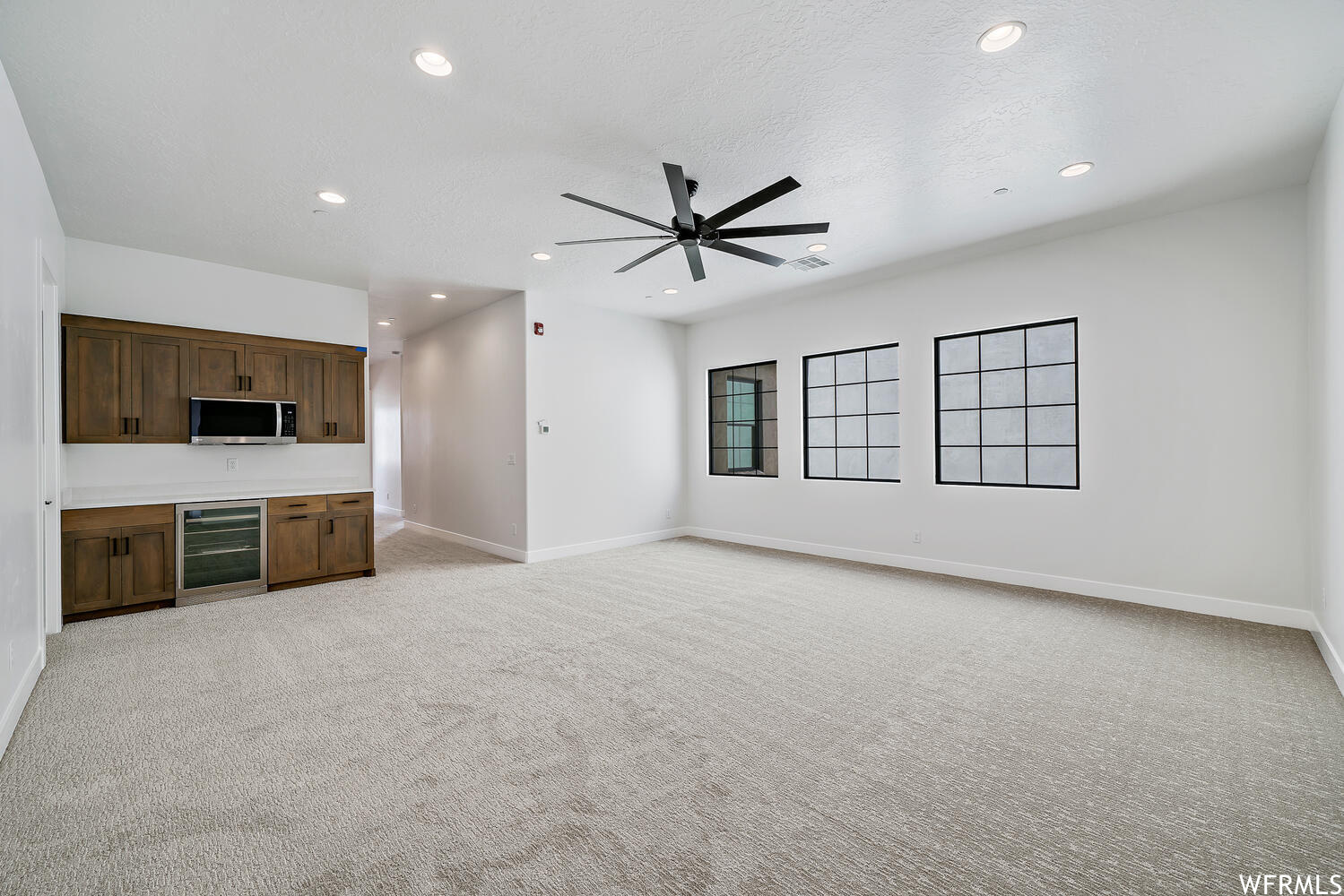 Interior space with a ceiling fan, microwave, and light flooring