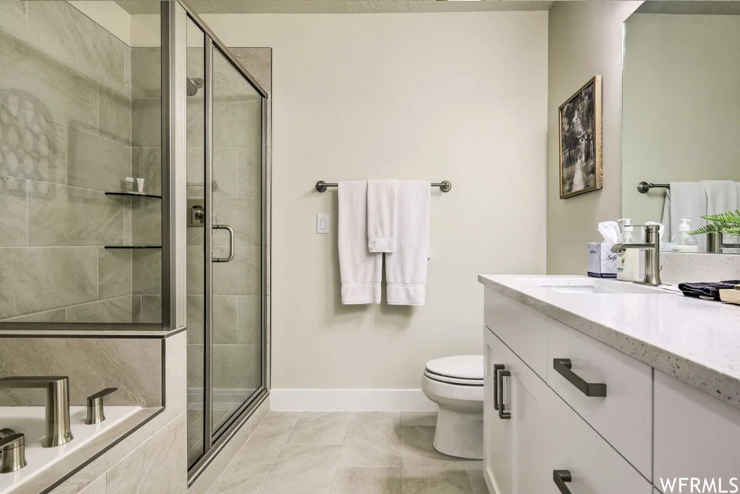 Master bath with full bathroom with tile flooring, toilet, mirror, vanity, and separate tub and shower