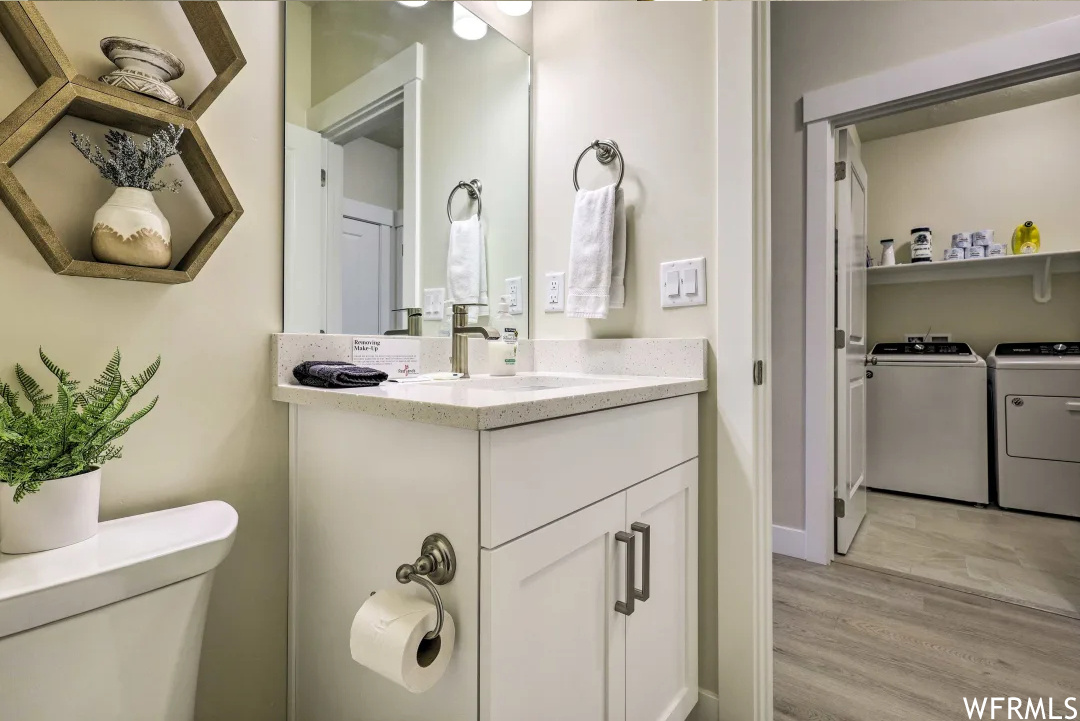 Half bath featuring tile floors, separate washer and dryer, toilet, mirror, and vanity