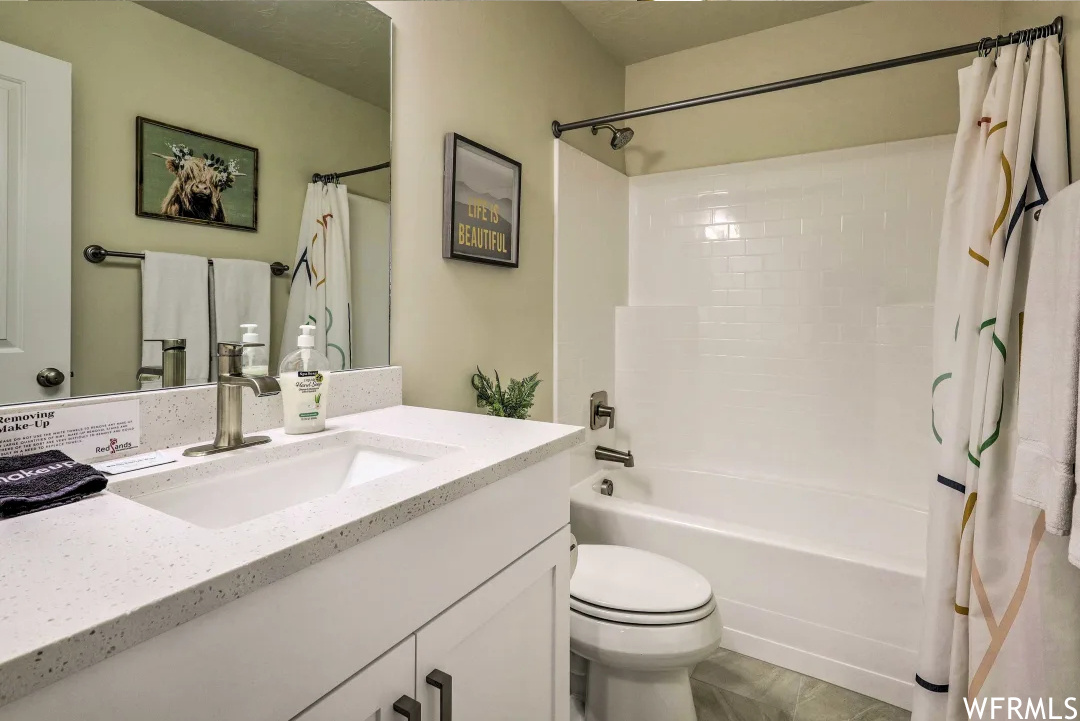 Full bathroom featuring mirror, toilet, large vanity, shower curtain, and bathtub / shower combination