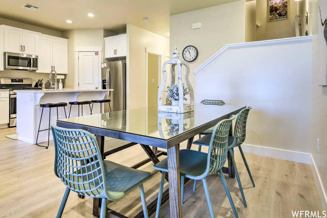 Wood floored dining space with a breakfast bar and stainless steel microwave