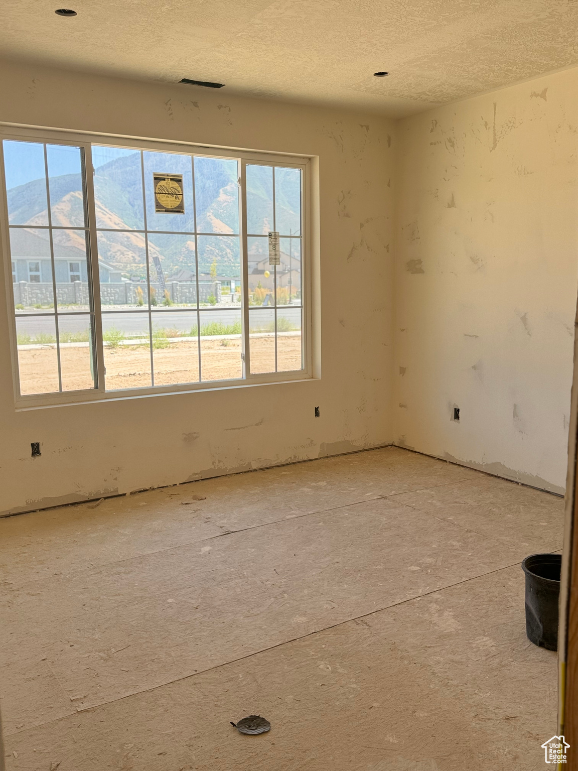 Spare room featuring a mountain view, a textured ceiling, and a healthy amount of sunlight