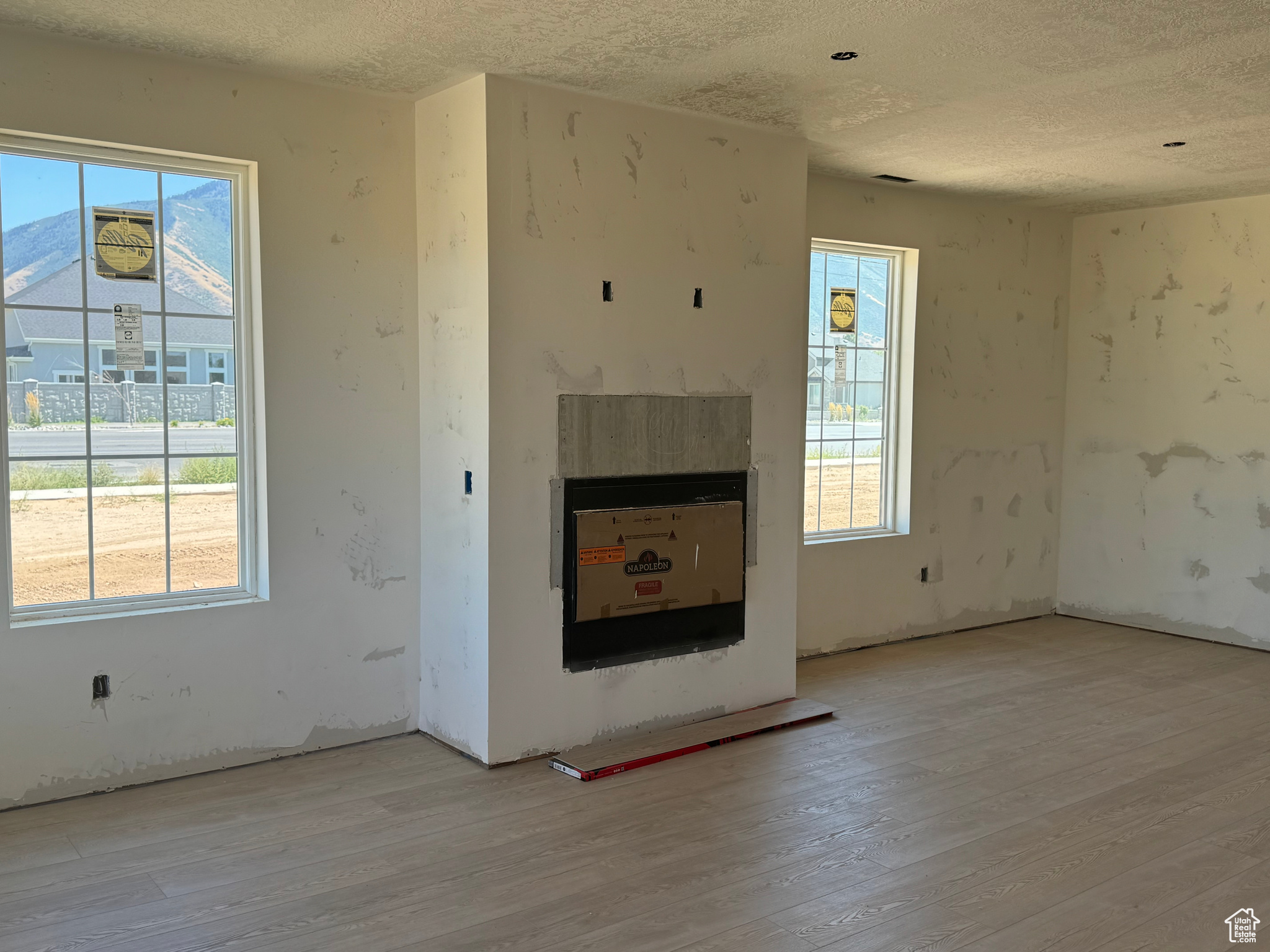 Unfurnished living room featuring a textured ceiling, a healthy amount of sunlight, and light hardwood / wood-style flooring