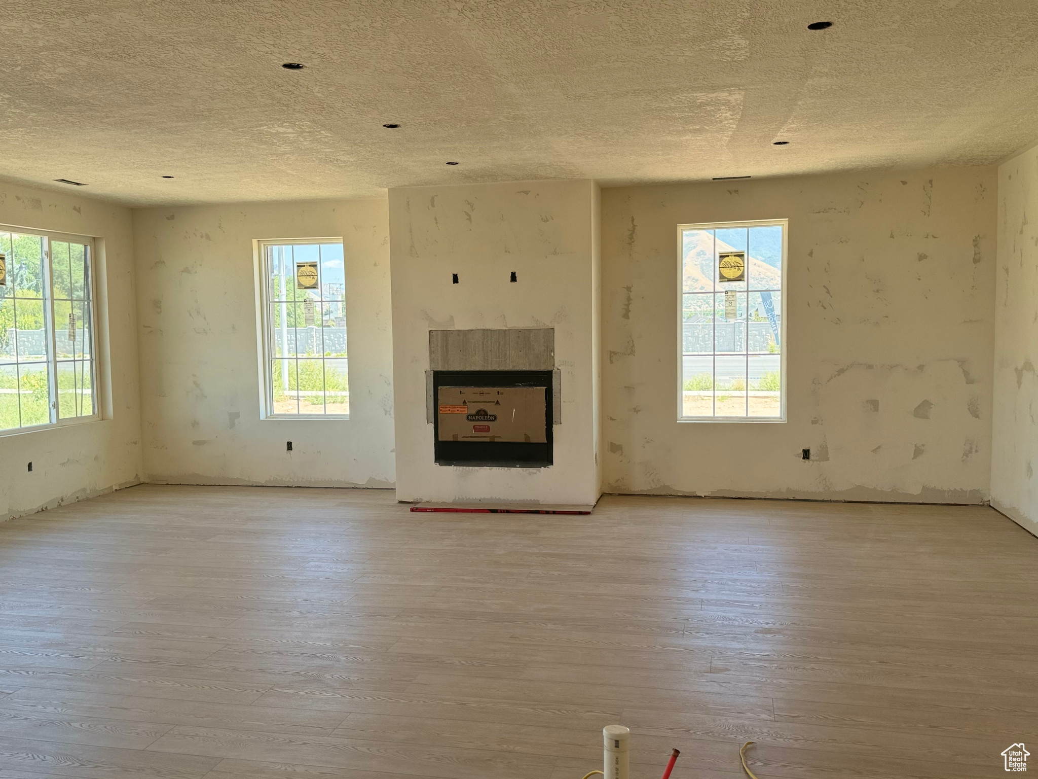 Unfurnished living room with a wealth of natural light, light hardwood / wood-style flooring, and a textured ceiling