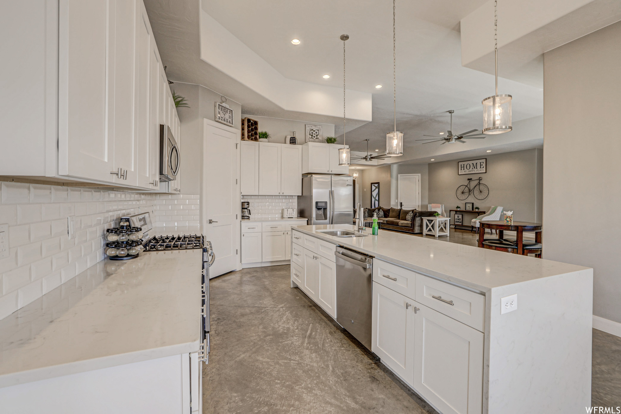 Kitchen featuring a ceiling fan, range oven, refrigerator, stainless steel dishwasher, microwave, light countertops, light tile floors, pendant lighting, and white cabinets