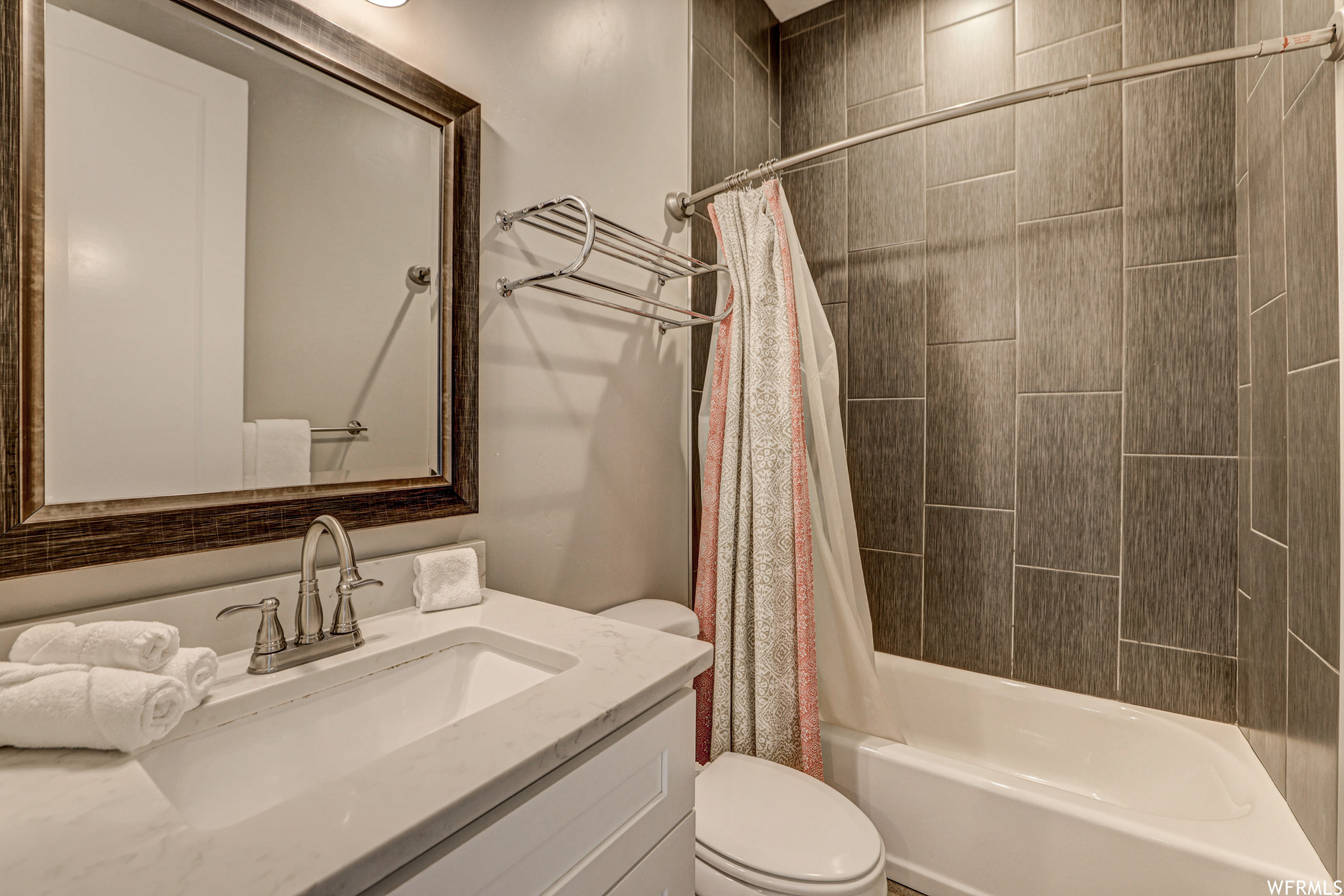 Full bathroom with mirror, shower curtain, toilet, bathtub / shower combination, and vanity