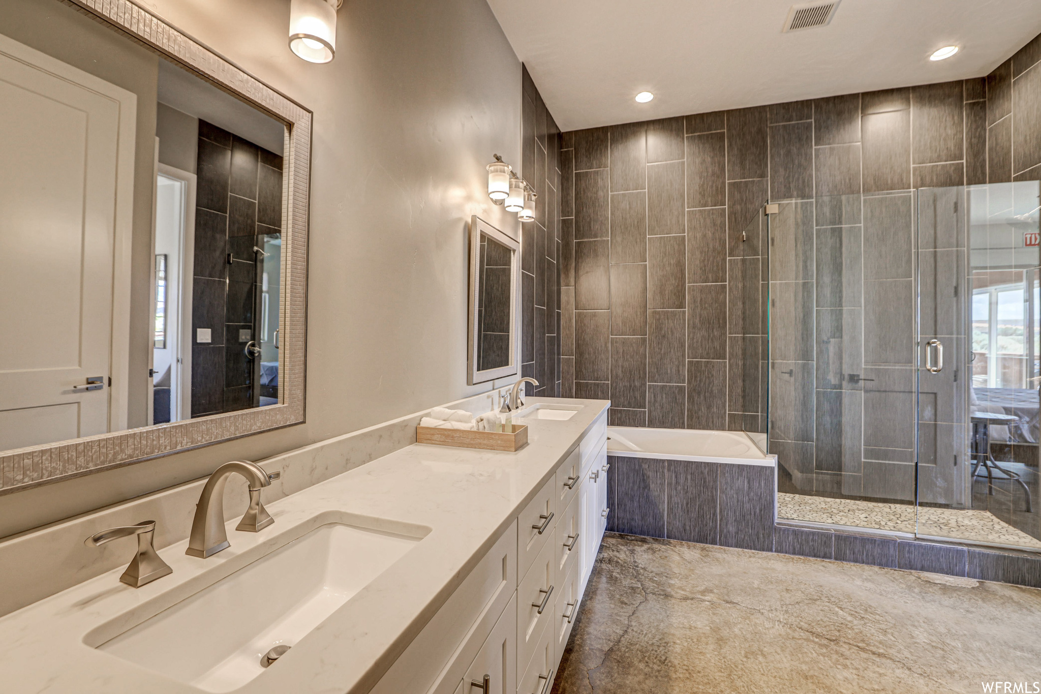 Bathroom featuring dual large vanity, separate shower and tub enclosures, and mirror