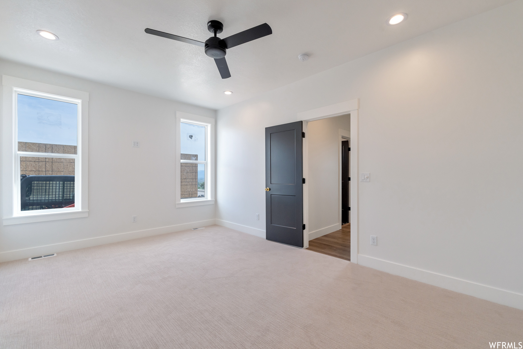 Empty room featuring hardwood floors, natural light, and a ceiling fan