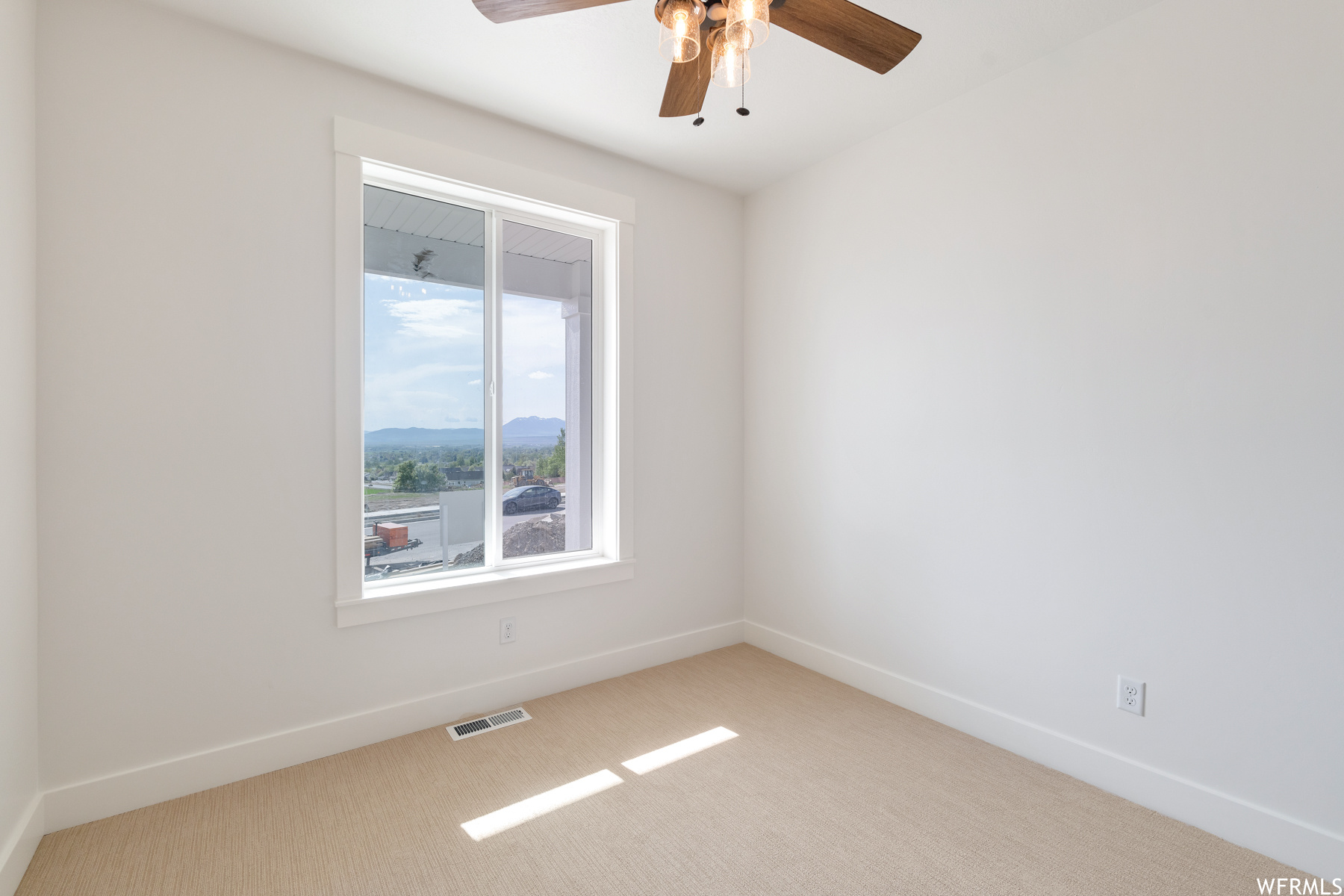 Carpeted empty room with natural light and a ceiling fan