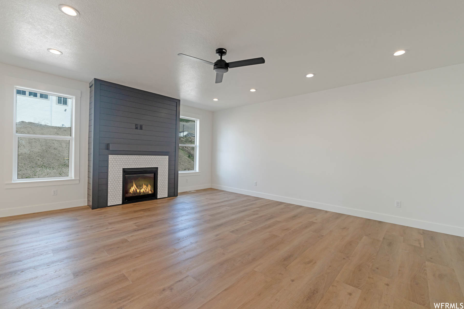 Living room with hardwood floors, natural light, a ceiling fan, and a fireplace